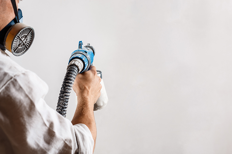 worker painting wall with spray gun white color 2